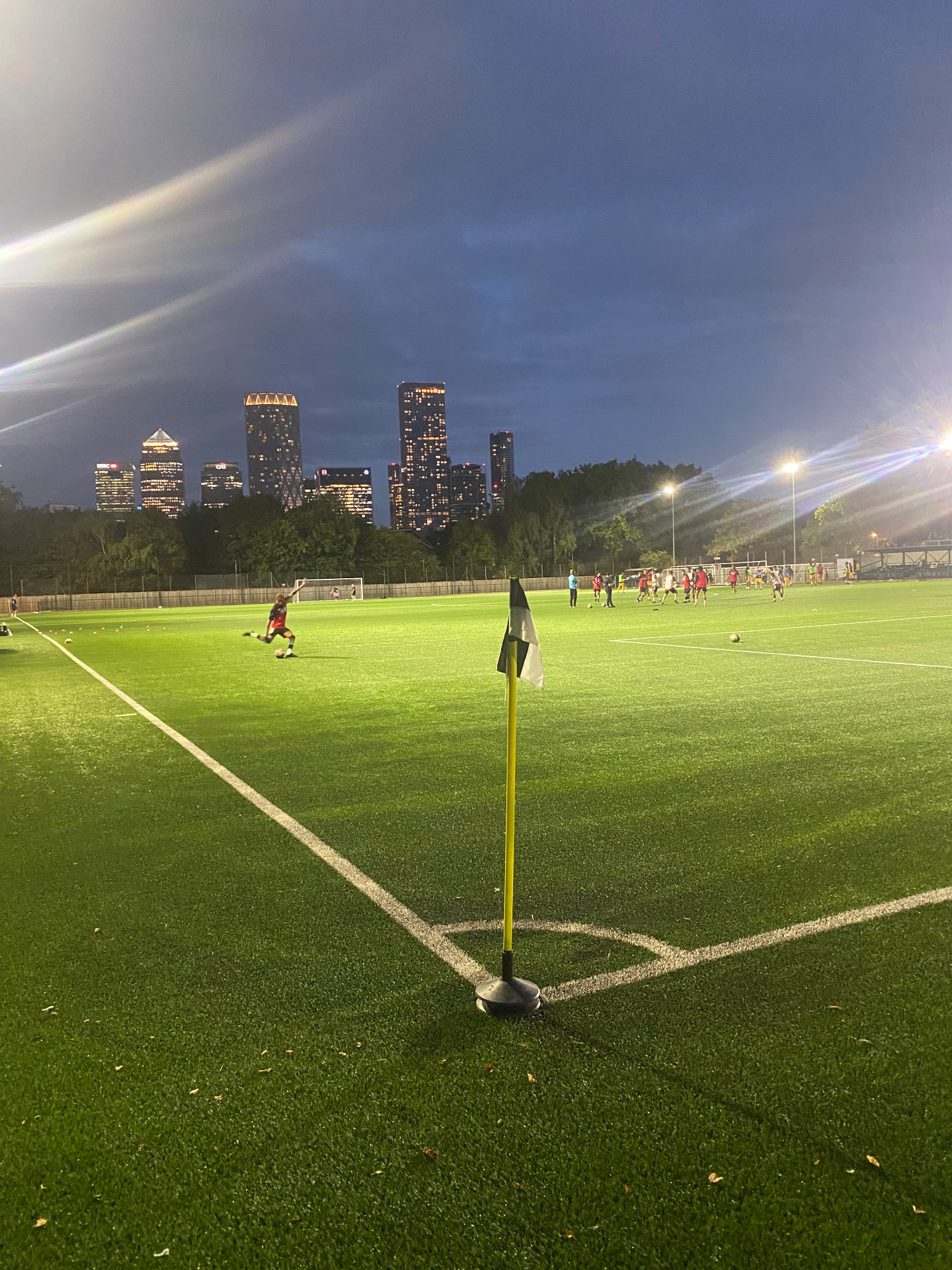 An evening match at St Paul's Sports Ground with the London skyline beyond the pitch