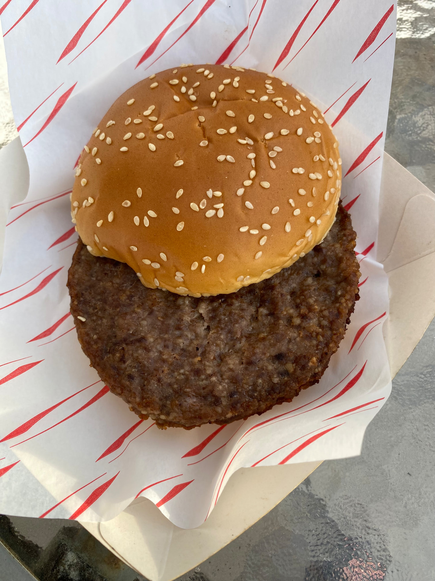 The same burger open, showing a charred patty wider than the bun
